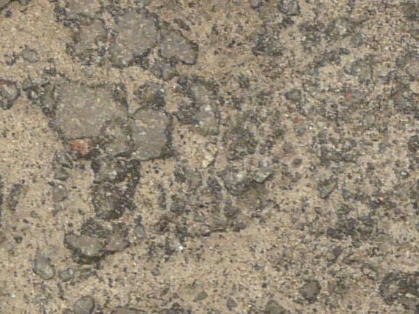 Grey asphalt texture covered in thick, shallow cracks and areas of dark, crumbling rock.